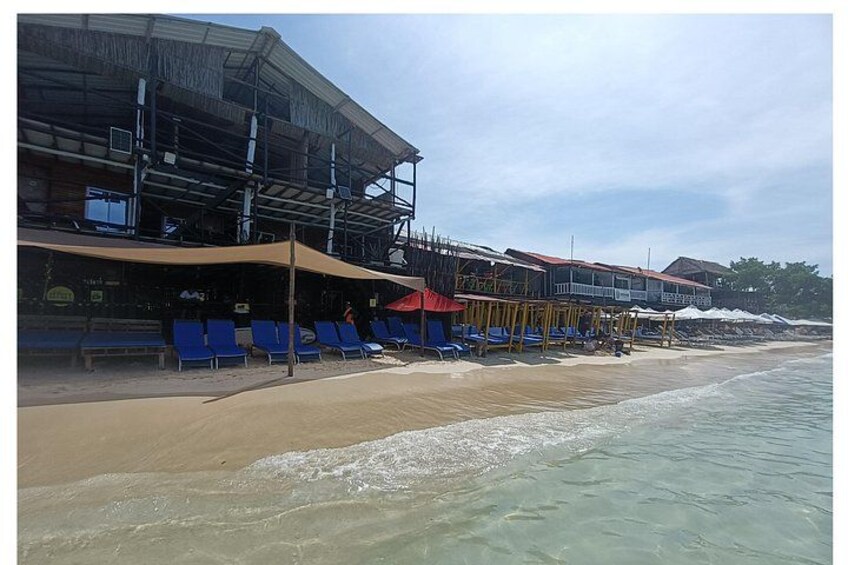 Een strand met blauwe ligbedden, een gebouw in aanbouw en een heldere lucht. 4