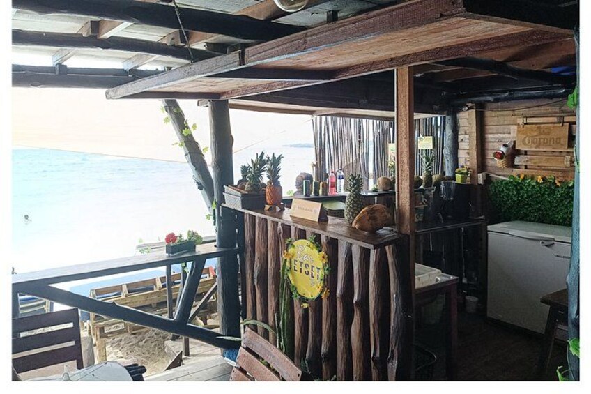 A rustic outdoor bar with wooden beams and a view of the ocean. 2