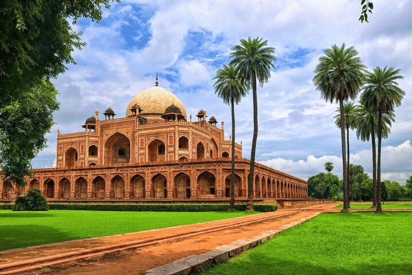 A large, ornate building with a dome and arched windows, surrounded by green fields and palm trees. 5