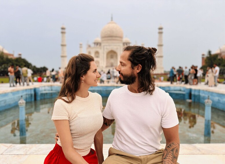 A couple sitting by a pool with the Taj Mahal in the background. 1