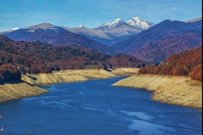 A lake surrounded by mountains and autumn-colored trees. 5