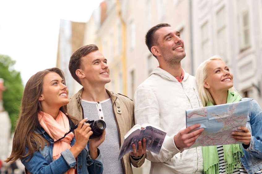 Four people standing on a street, one holding a camera and another holding a map. 1