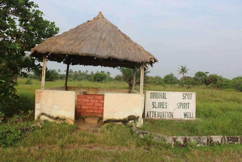 A thatched-roof hut with a sign reading "ORIGINAL SLAVES SPIRIT ATTENUATION WELL". 2
