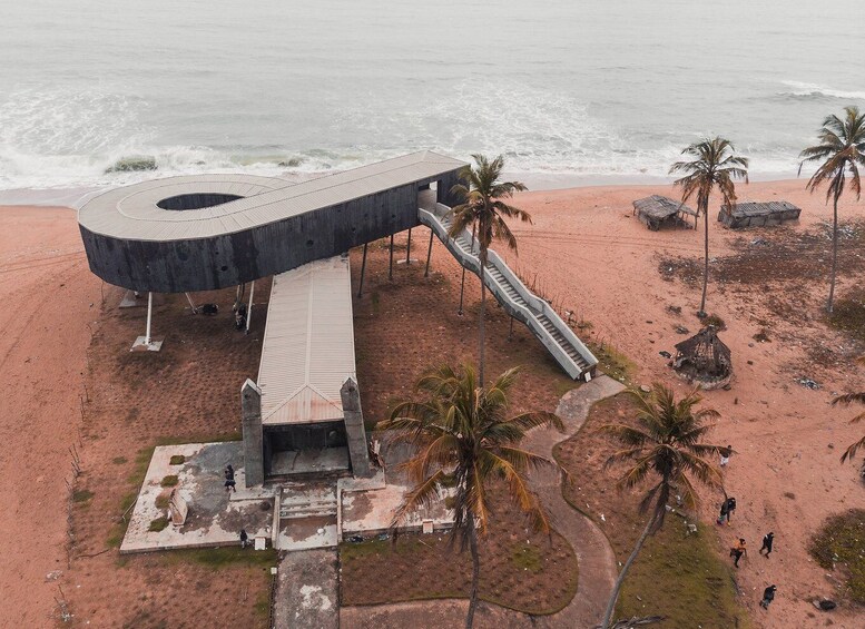 A modern structure with a circular top and a staircase leading down to a beach. 4