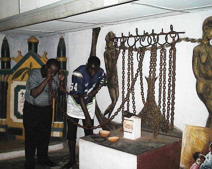 A person taking a photo of a statue, another person standing nearby, and a chain hanging from the statue. 5