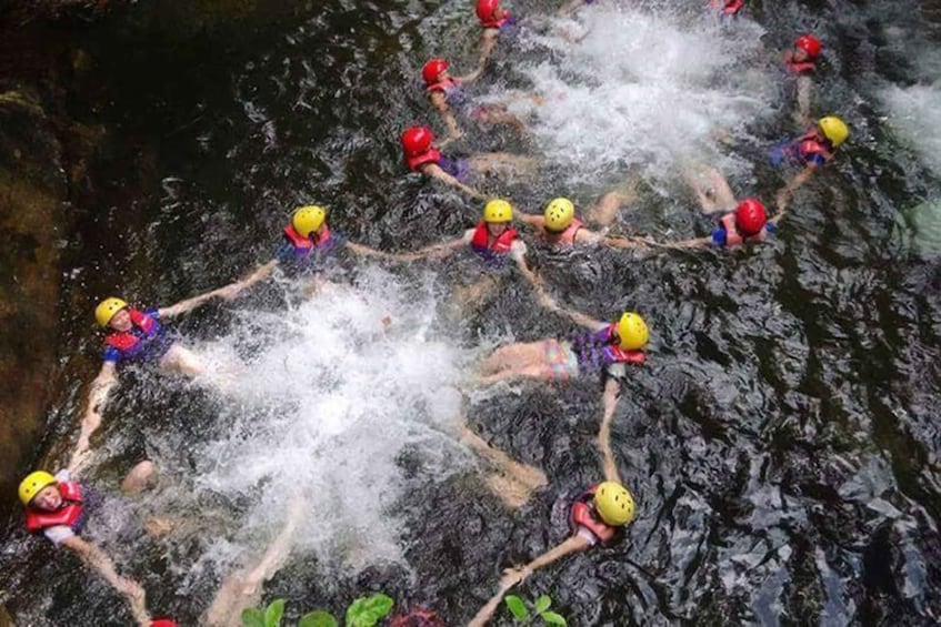 A group of people in water, wearing helmets and life jackets, engaged in a water-based activity. 5