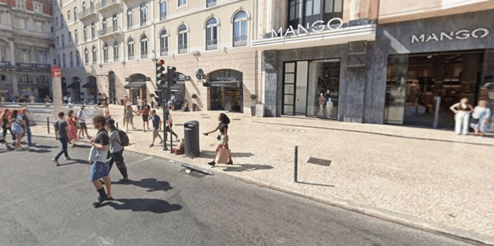 En gata med fotgängare, en butik som säljer mango och klassisk arkitektur. 2