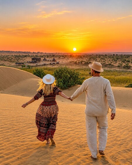 A couple walking on a sandy beach at sunset, holding hands. 1
