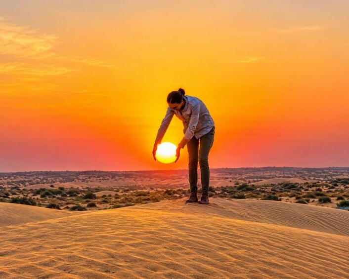 En person står på en sanddune i solnedgangen. 4