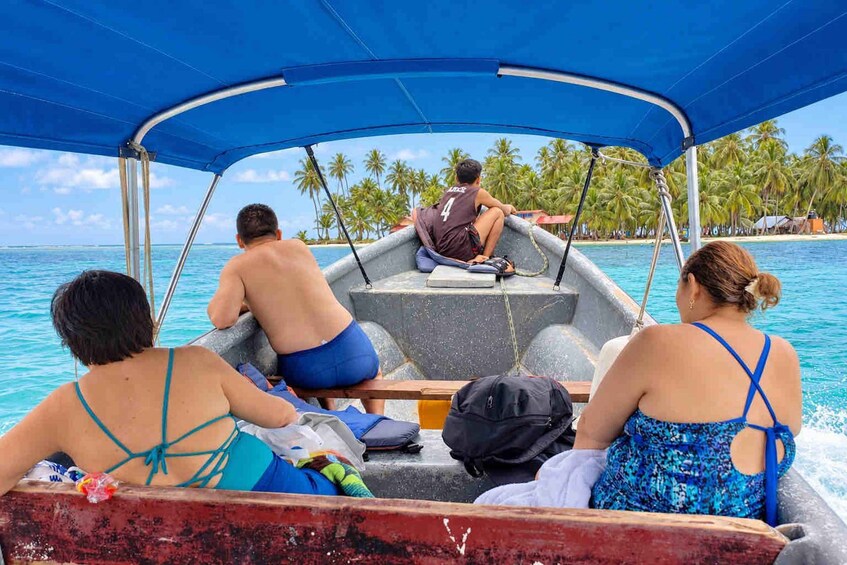A boat with a blue canopy, passengers, and a tropical beach with palm trees in the background. 4