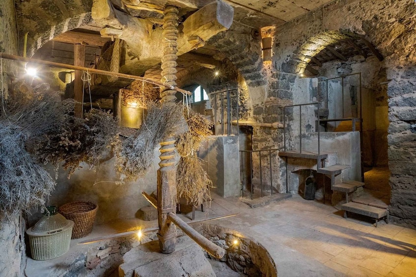 A stone interior with a wooden mill, stone walls, and a rustic atmosphere. 1