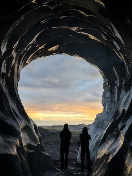 Una cueva de hielo extensa con vistas al cielo y montañas distantes. 4