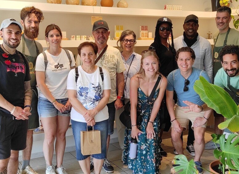A group of people standing indoors, some holding shopping bags. 5