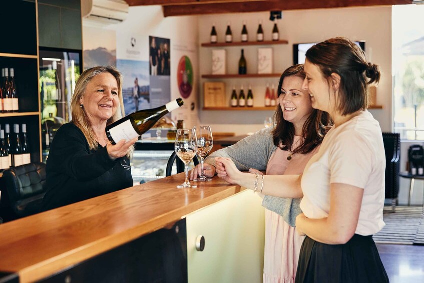 A bar setting with a wooden counter, wine bottles, and glasses. 2