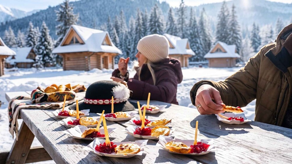 A group of people enjoying pastries outdoors with snow-covered houses in the background. 5