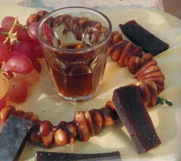 A plate with grapes, a glass of iced tea, and chocolate-covered nuts. 5