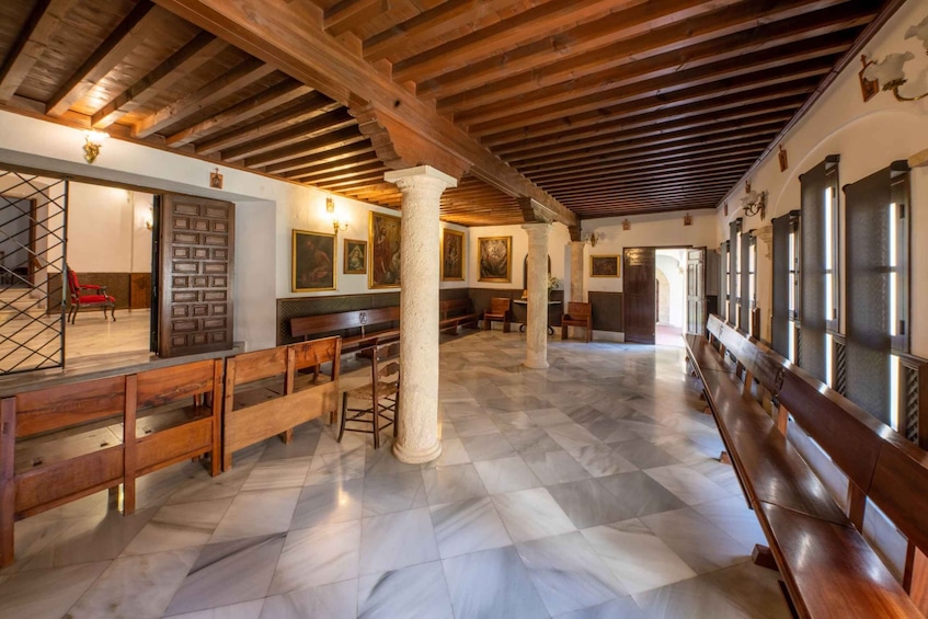 A spacious hall with wooden benches, a marble floor, and a high wooden ceiling. 3