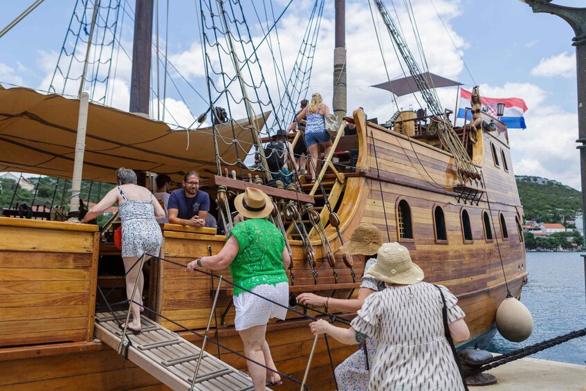 People boarding a wooden ship with a Croatian flag. 2