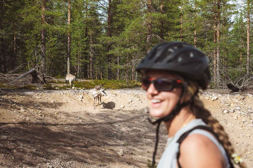 A person with a helmet and sunglasses, a forested area with a dirt path, and a small animal in the background. 4