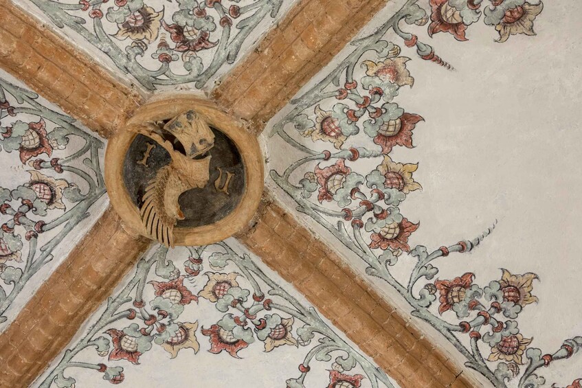 A ceiling with a central circular medallion featuring a lion's head, surrounded by floral patterns. 3