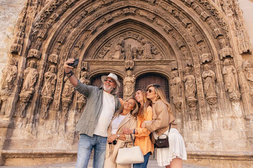 A group of people taking a selfie in front of a Gothic cathedral with intricate stone carvings. 4