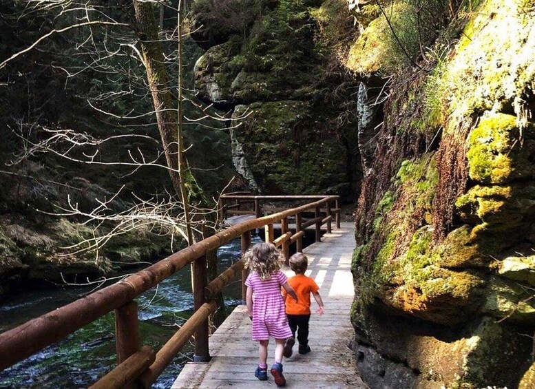 A wooden bridge over a river with rocky cliffs on either side. 5