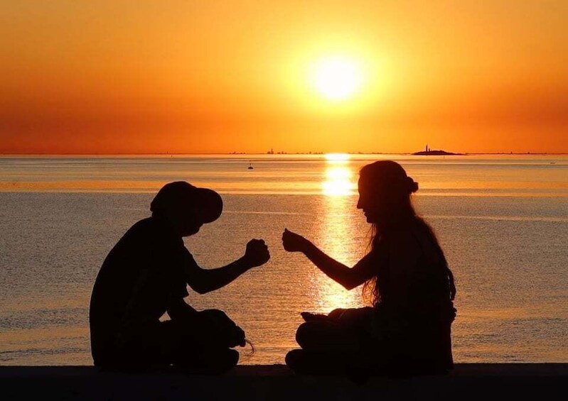 Two people sitting on the beach at sunset. 1