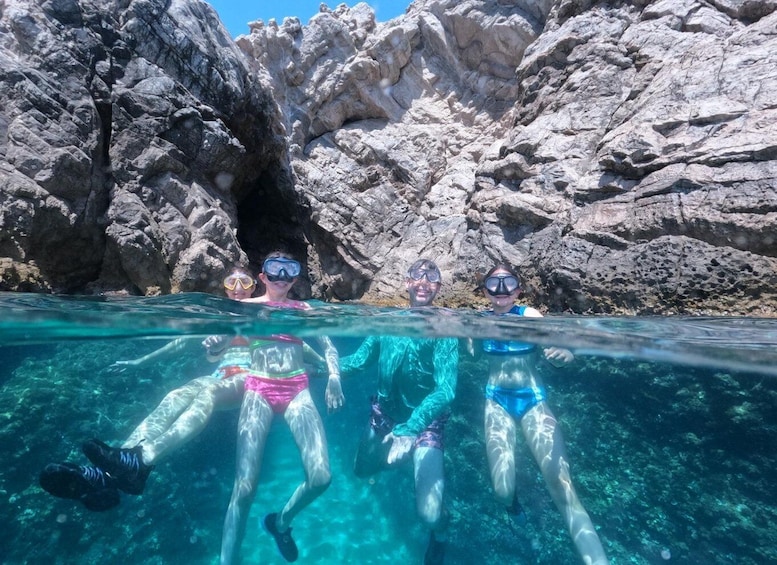Three people snorkeling in clear water with rocky cliffs in the background. 5