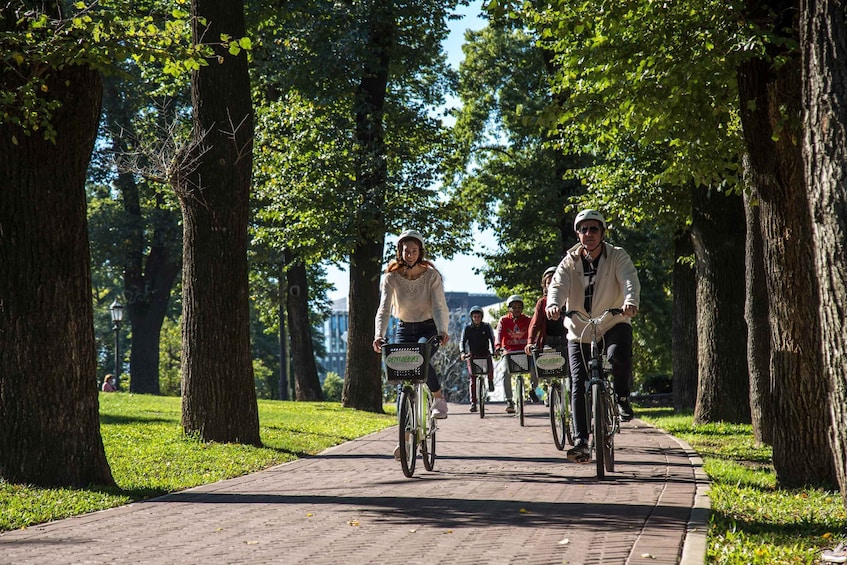 Mensen fietsen op een pad langs bomen in een park. 1