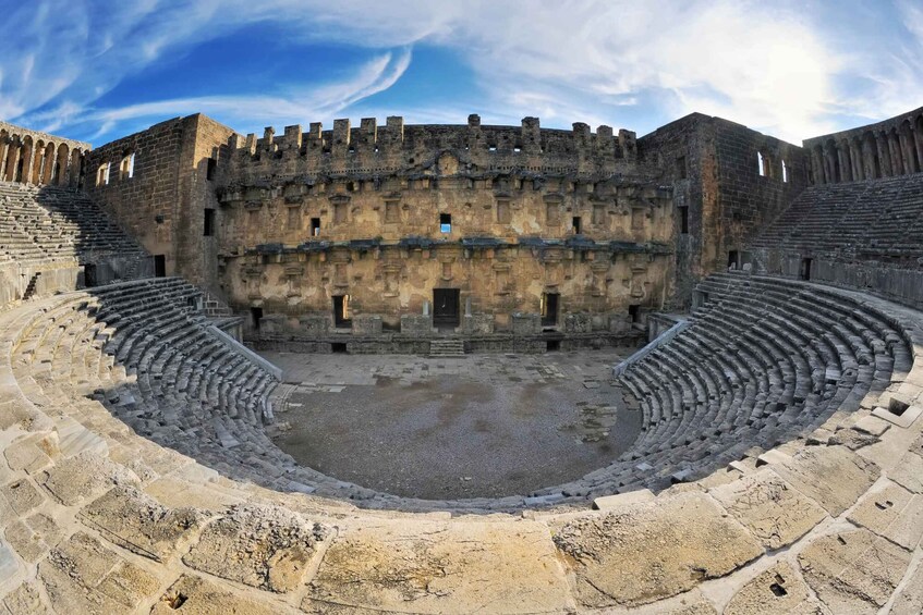 An ancient amphitheater with stone seating and a central stage. 1