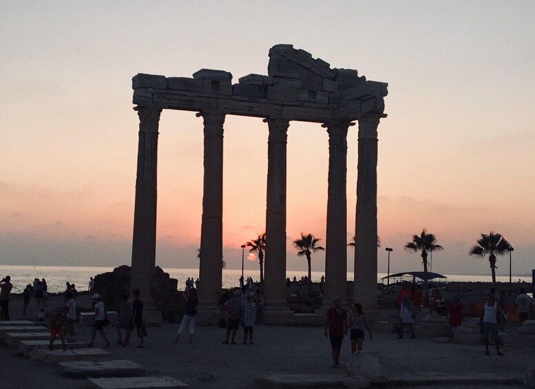 Ancient columns at sunset with people around. 5