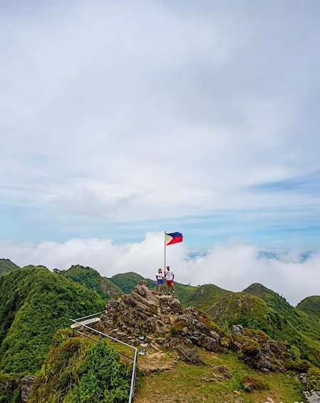 A flag on a rocky peak with lush green hills in the background. 5