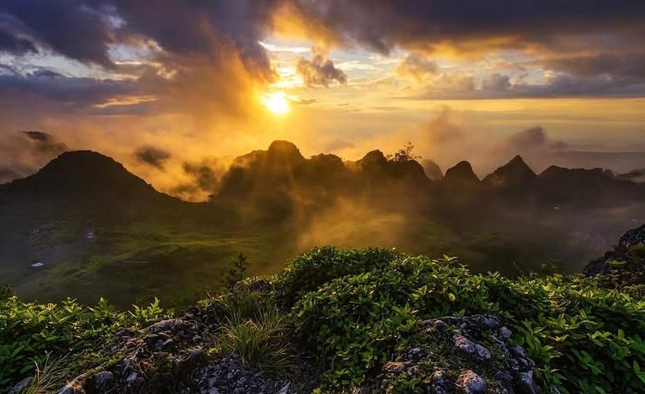 A mountainous landscape with a sunrise or sunset, casting a warm glow over the peaks and valleys. 3