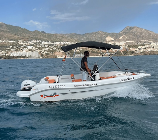 Una lancha rápida blanca llamada 'Oceanautic' con una persona manejándola, navegando sobre aguas tranquilas con un paisaje montañoso al fondo. 4