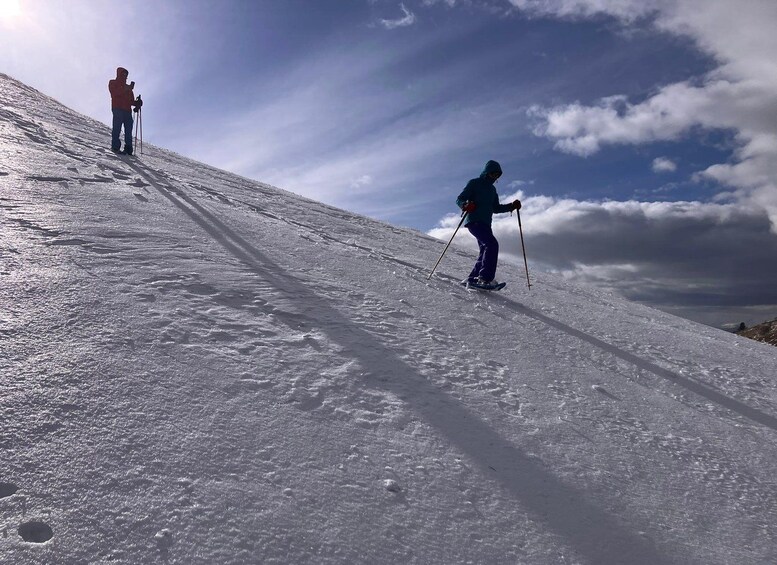 A snowy mountain slope with two skiers descending. 2