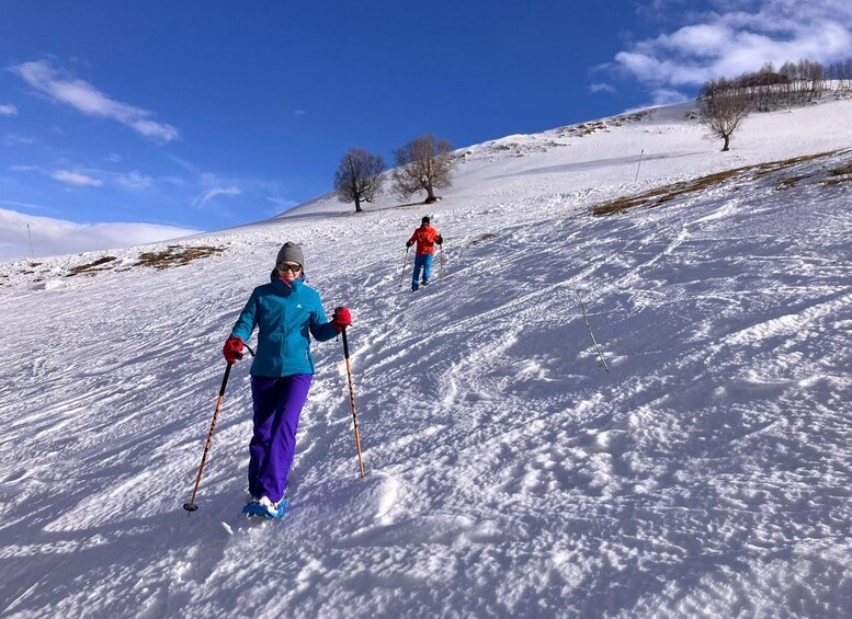 Two people cross-country skiing on a snowy slope with a clear sky. 3