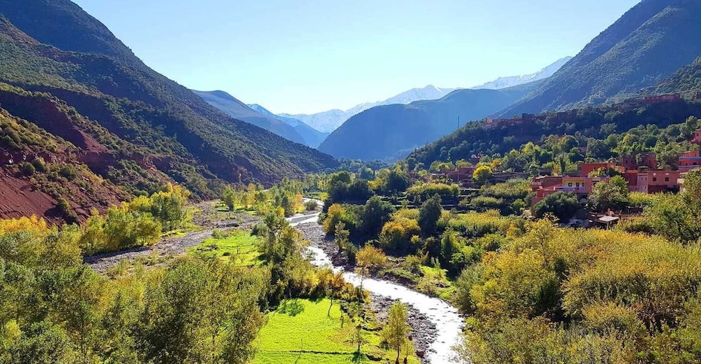 A valley with a river, green fields, and houses on the hills. 3