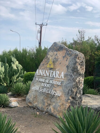 A large rock with the text "ANANTARA AL JABAL AL AKHIDAR RESORT" and some Arabic script. 1