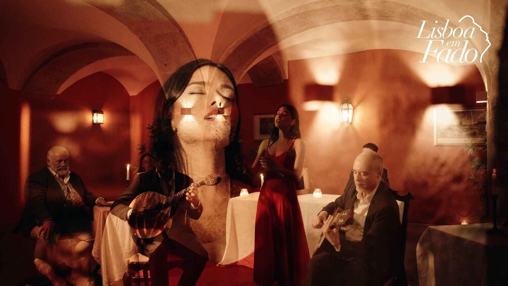 A dimly lit room with people seated around tables, a guitar, and a candle on a table. 4