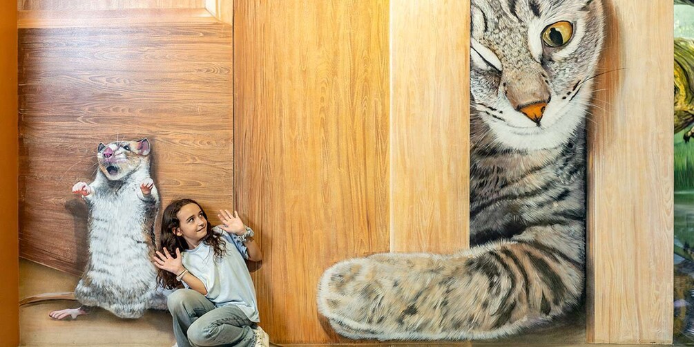 Un bambino interagisce con un grande murale raffigurante un gatto. 2
