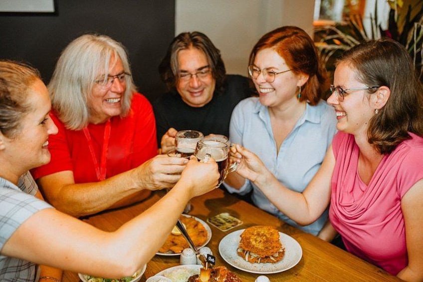Un grupo de personas brindando con bebidas alrededor de una mesa con comida. 2