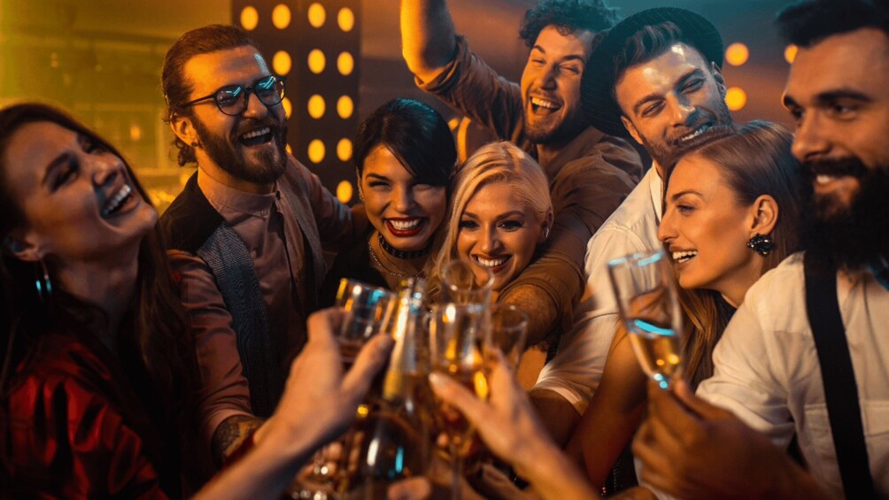 A group of people toasting with drinks in a dimly lit setting. 1