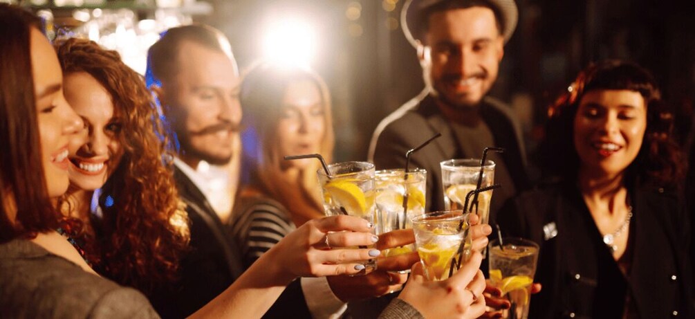 A group of people toasting with drinks that contain lemon slices and straws. 5