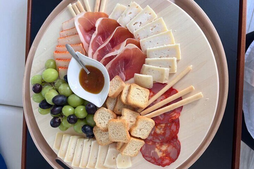 A charcuterie board with various cheeses, meats, grapes, and bread. 3