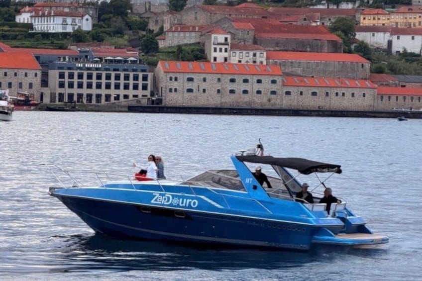 A blue speedboat with 'Zad Euro' on its side, moving on calm water with a cityscape in the background. 5