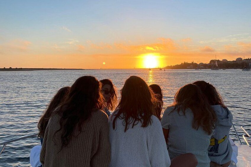 Un atardecer sobre una masa de agua con un grupo de personas en un bote. 3