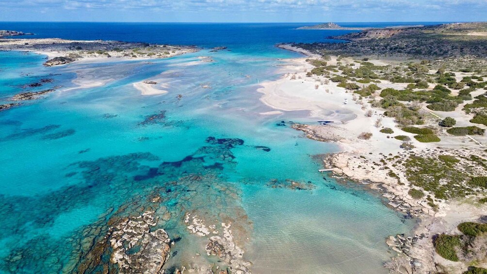A coastal landscape with clear turquoise waters, sandy beaches, and rocky outcrops. 1