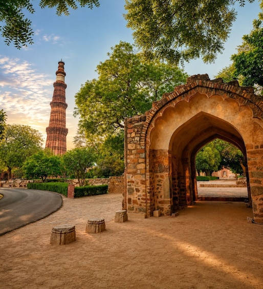 A stone archway, a tall minaret, and a curved road in a park. 1