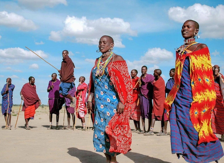 A group of people in traditional attire walking in a desert landscape. 2