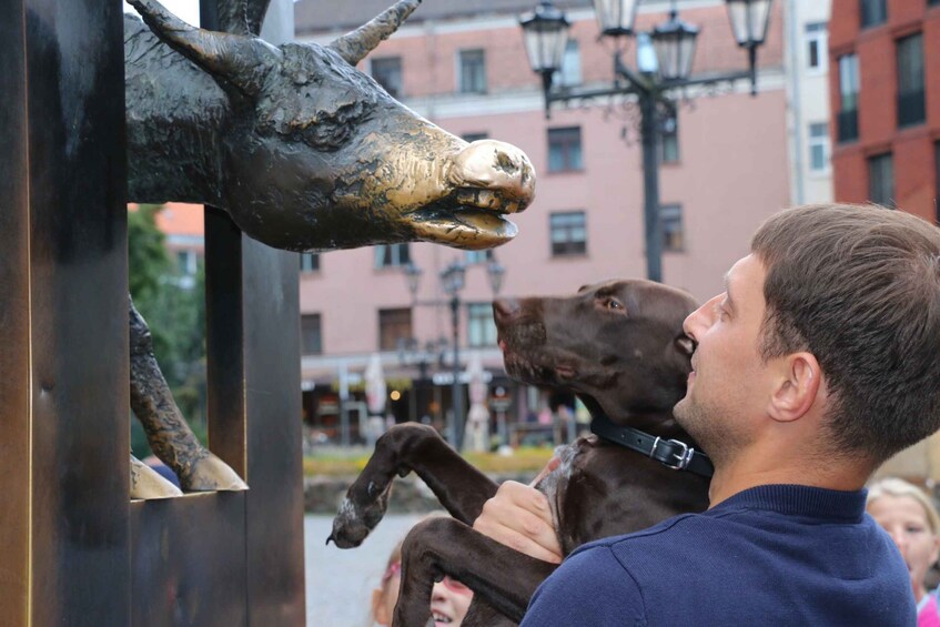 A person holding a large bronze sculpture of a bull's head. 3